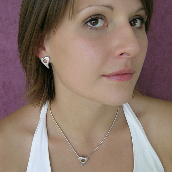 Model wears Annika Rutlin sterling silver Amitie heart stud earrings and necklace