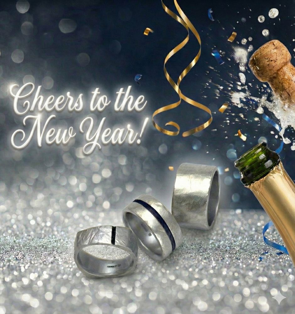 Two silver rings with a bottle of champagne and confetti on a glittery surface with 'Cheers to the New Year!' text.