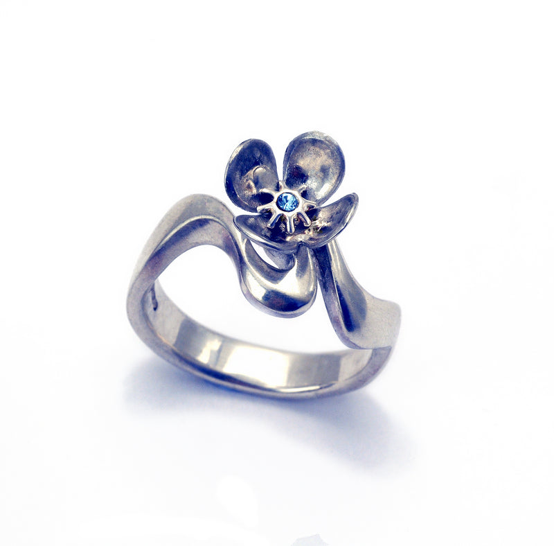Pretty flower ring set with blue topaz on a flowing band. An adaptation of a ring from the Luna Collection by Annika Rutlin. We are happy to adapt any oof our designs to make something special and unique to you. Simply contact us to find out more