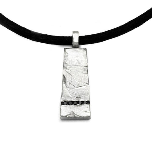 A solid silver rough textured pendant with a line of bleck diamonds by Annika Rutlin